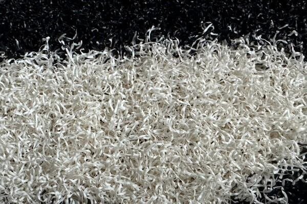 discolored white padel turf lines next to black grass