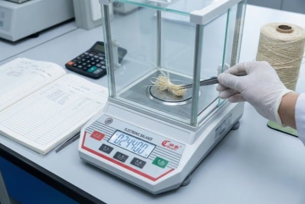 engineer weighing artificial grass yarn to determine dtex