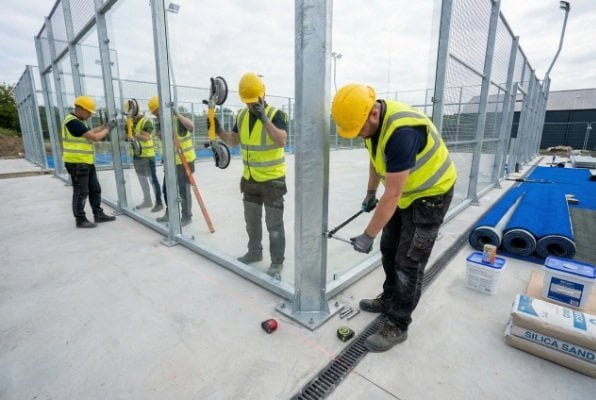 workers installing padel court glass