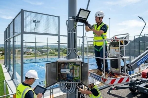 Technicians installing padel court lighting system