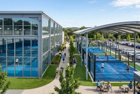 Modern outdoor padel courts beside a glass sports building